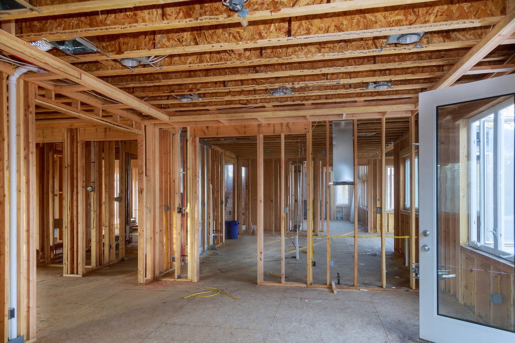 Interior view of a house under construction in Colorado Springs, highlighting exposed wooden framing, ceiling beams, and unfinished walls—ideal for new construction electrical services installation.